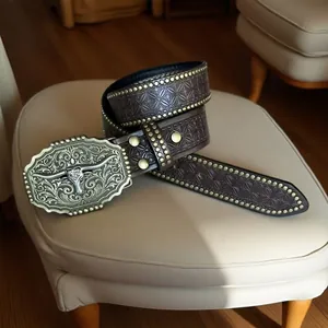 Primo piano di una cintura vintage in pelle da cowboy con fibbia a testa di toro ornata e borchie.
