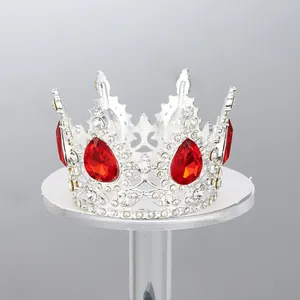 Vista detallada de una elegante corona de plata con cristales rojos en soporte blanco