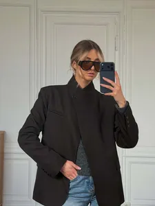 Detail showing the stand-up collar and asymmetrical design of the black blazer