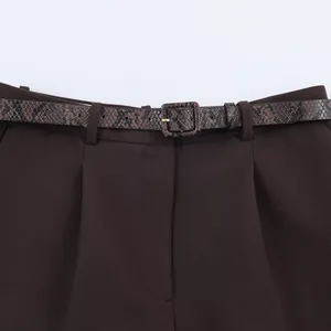 Detailed view of dark brown trousers featuring a stylish snakeskin textured belt