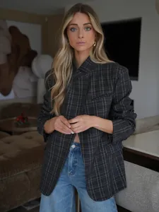 Detail of a grey plaid stand-collar blazer jacket on a model in a stylish indoor setting