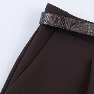 Detail view of dark brown women's casual pants featuring a stylish snakeskin print belt.