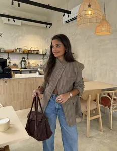 Detailed view of fashionable plaid stand-up collar blazer in a cozy cafe setting