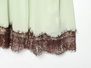 Detailed macro view showing the exquisite brown lace hem on a mint green dress.