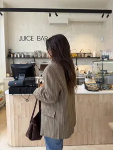 Close-up detail of oversized brown plaid checkered blazer jacket in a modern cafe setting