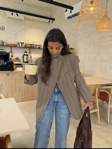 Model wearing a stylish plaid stand collar blazer and blue jeans in a cozy cafe setting.