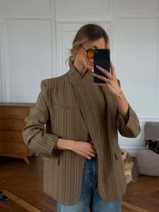 Detailed look of a brown plaid blazer with a unique stand-up collar and chic asymmetrical cut.