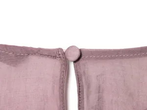 Dettaglio di una camicetta in chiffon rosa antico con scollatura posteriore e bottone