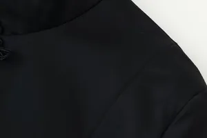 Close-up of solid black stand collar jacket featuring traditional knot button detail.