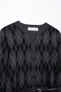 Close-up of grey argyle knit cardigan with round neck and matching belt details.