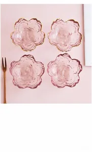 Vue de dessus de quatre bols en verre rose en forme de fleur de cerisier avec bords dorés
