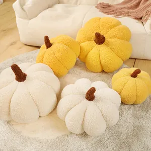 Gros plan de coussins décoratifs en peluche citrouille en polaire sherpa jaune et blanche.