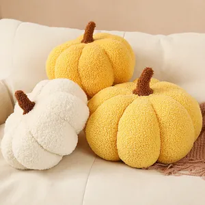 Gros plan de trois coussins décoratifs en peluche citrouille en tissu bouclé jaune et blanc