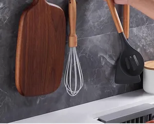 Heavy-duty transparent adhesive wall hooks holding kitchen tools on a marble wall