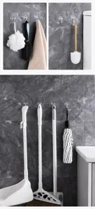 Detailed macro view of strong adhesive wall hooks holding mops and brooms on tile.