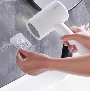 Close-up showing hairdryer heating a transparent adhesive wall hook on bathroom tiles