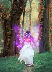 Girl wearing glowing purple LED butterfly fairy wings for costume party in magical forest