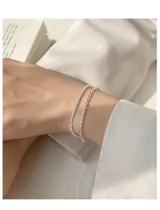 Detailed close-up of 925 silver plated rice grain and sparkling bracelets on wrist