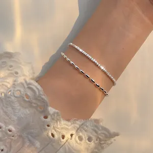 Close-up of double-layer silver sparkling star and rice grain bead bracelets on wrist.