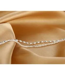 Macro detail of double-layer silver-plated bracelet with rice beads and starry chain