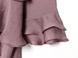 Primo piano dell'orlo a balze di un top casual color malva che mostra la trama del tessuto.