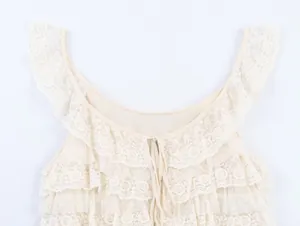 Vue détaillée des volants en dentelle crème et du décolleté à cordon de serrage chic.