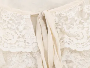 Gros plan sur le tissu en dentelle florale crème et le design à nouer d'un chemisier.