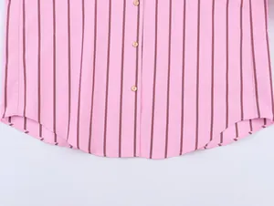 Close-up detail of a pink striped casual shirt showing the curved hem and gold buttons