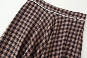 Detailed view of a brown plaid skirt featuring delicate white lace trim on the waist.