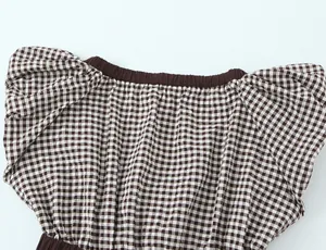 Detalle de blusa a cuadros marrones con escote elástico y mangas de globo modernas.