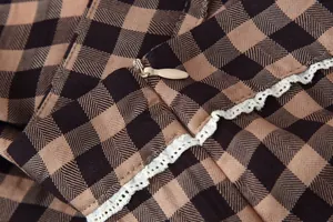 Close-up of hidden zipper and white lace trim on brown checkered plaid skirt fabric.