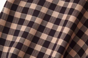 Close-up macro view of classic brown small checkered fabric texture for trendy fashion skirt