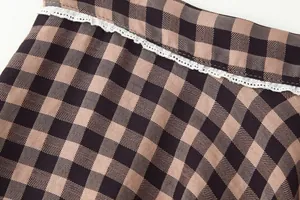 Close-up of brown and black checkered fabric with delicate white lace trim