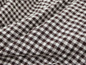 Primer plano detallado de la textura de la tela de cuadros vichy pequeños en marrón y blanco.
