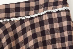 Close-up of gingham fabric texture with white lace trim detail on a skirt.