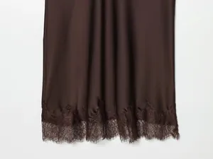 Detailed macro view showing the intricate lace hem of a dark brown satin midi skirt