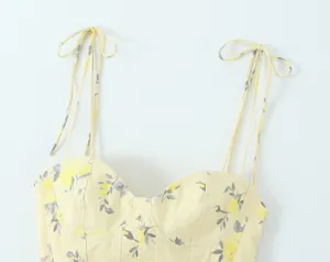 Primer plano de top de tirantes con estampado floral amarillo y tirantes ajustables.