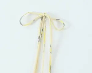 Detalle del tirante con estampado floral amarillo anudado en un lazo en top
