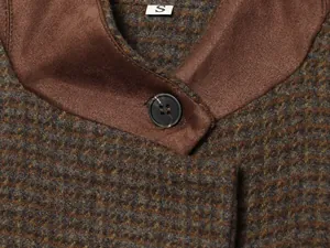 Macro detail of vintage plaid blazer featuring brown patchwork collar and black button