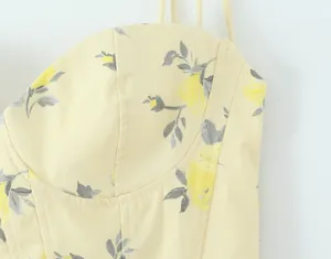 Detalle de una camisola con estampado floral amarillo, tirantes finos y costuras.