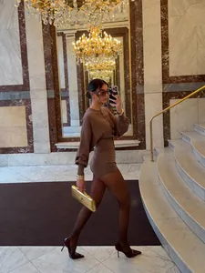 Side view of elegant woman in brown knit cardigan and shorts set in luxury interior