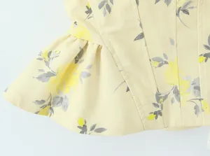 Detalle de cerca de la tela con estampado floral amarillo y costuras en una blusa de tirantes