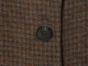 Macro detail of houndstooth wool fabric texture and black button on a jacket