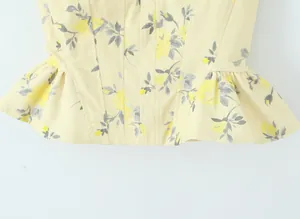 Primer plano del estampado floral amarillo y el dobladillo peplum en un top ajustado.