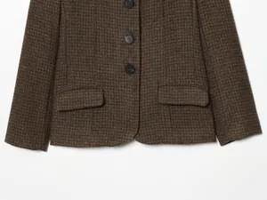 Detailed macro view of a brown checkered blazer featuring black buttons and flap pockets.