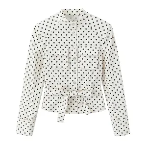 Detalle de chaqueta tipo camisa con lunares, bolsillos frontales y cinturón lazo