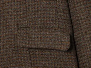 Detailed macro shot of the premium brown checkered tweed fabric on a stylish blazer jacket