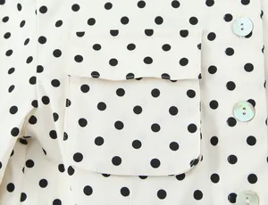 Vista macro de la chaqueta tipo camisa de lunares con bolsillo y botones iridiscentes