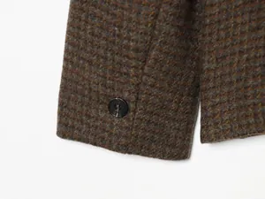Close-up detail of blazer sleeve cuff featuring classic plaid pattern and dark button