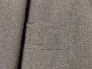 Nahaufnahme zeigt die feine Textur und Paspeltaschendetails eines grauen Blazers.